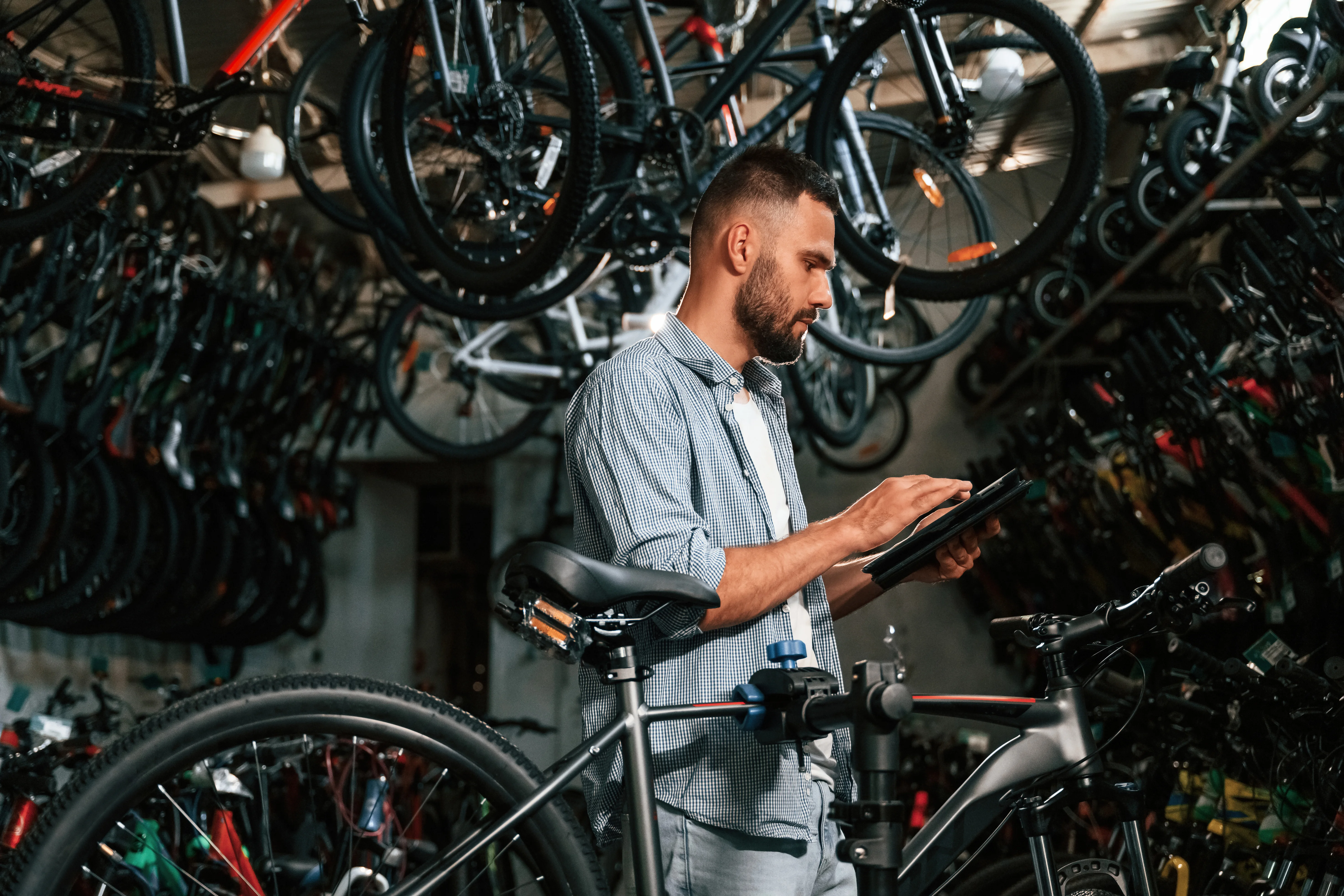 A mechanic checking stock on a tablet in a bike shop